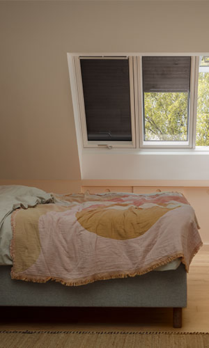 bedroom view of bed and shutters on one of three rooftop windows down to reduce light entering the room while staying somewhat bright