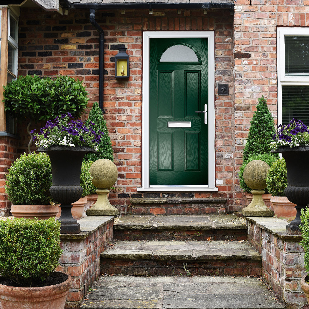 Front view of brick house with green door, flower pots with flowers