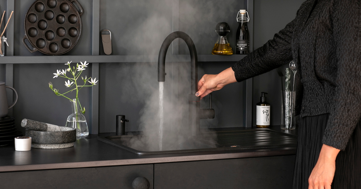 black sink and tap that is pooring out hot water with steam rising