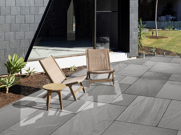 Grey sandstone paving with two wooden decking chairs with a small wooden table