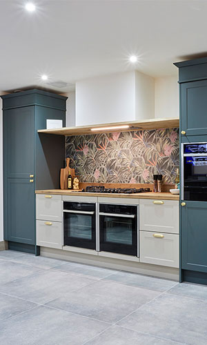 open cooking top area with gasoline green cupboards and white drawers with built in ovens and cieling fan