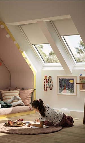 young woman writing in book with rooftop windows shining light into the room