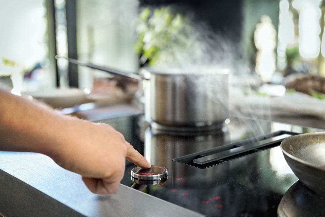 man turning dial on electric stove to vacume mist from pan on cookingtops internal air vacume