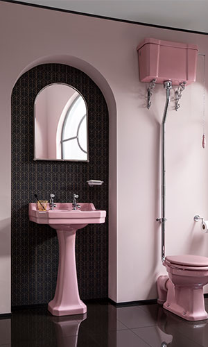 Pink sink, toilet and walls with black floor and black indented wallpaper with mirror