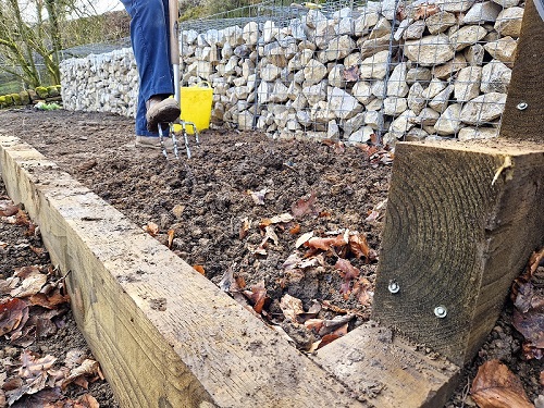 person with pitch fork digging inside wooden frame