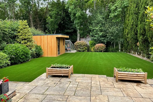 large ground view of garden with alot of plant life with smooth grass, shed, crop plots and stone slab paving