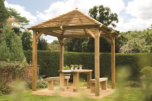Outdoor wooden seating eare with two benches and a table with wooden gazebo