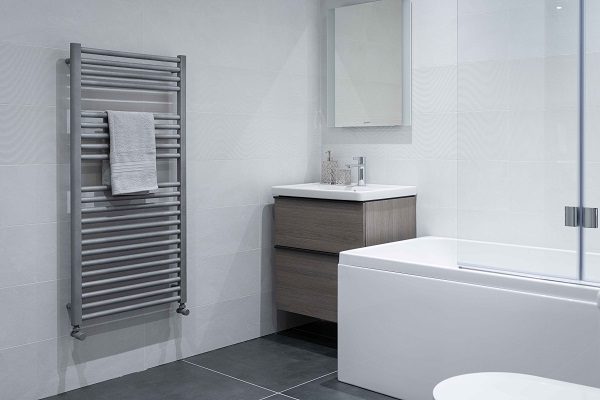 white bathroom with grey towel rack, mirror and sink with drawers