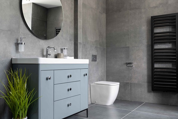 bathroom with grey walls, widde sink with drawers, circular mirror