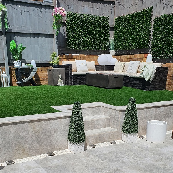 ground view of outdoor sitting area with fake grass, dark wood furnitureand steps up to the seating area