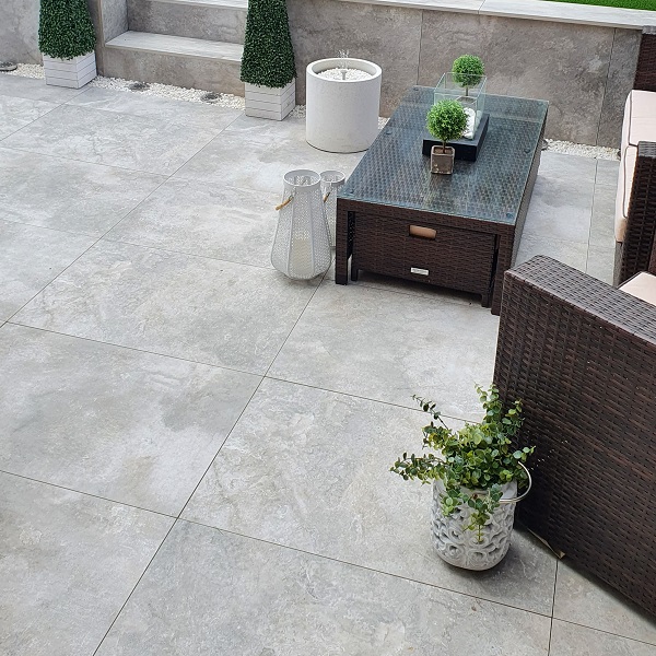 high view of grey paving with dark wooden tables and chairs and white plant pots