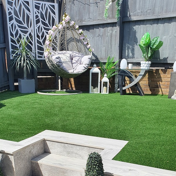 hanging chair on fake grass seating area with fake flowers between the grooves