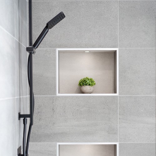 black shower attached to grey tiled walls with small indents for plants with built in lights