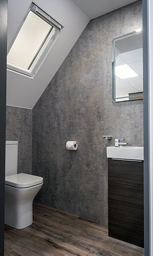 lavatory with grey granite like walls dark wood flooring, small sink with cupboard attached