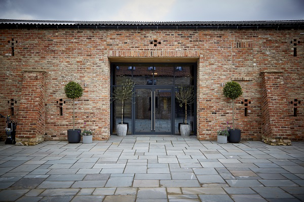 Front view of brick building with glass double doors and stone slab paving
