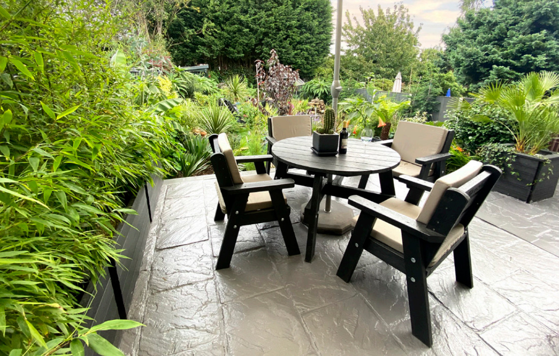 outdoor view of plaswood table and chairs on stone paving surrounded by bushes