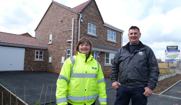 Man and woman stood outside of a brick house