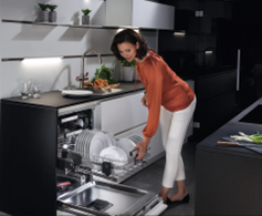 Woman using dishwasher that can raise the lower shelf for convenience