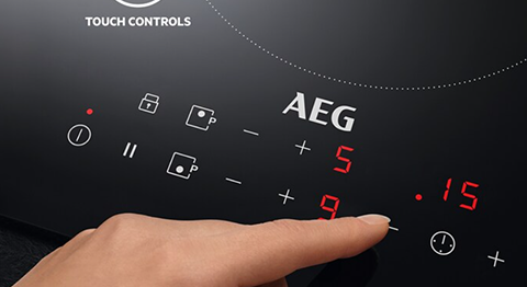 person ajusting heat using touch screen area on cooking top