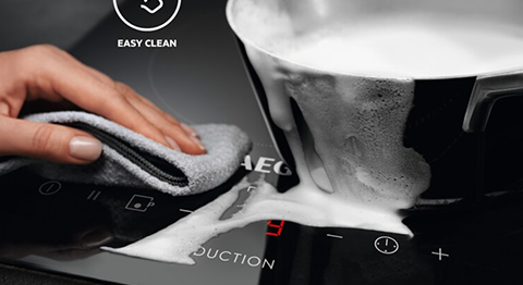 person cleaning spillage on cooking top