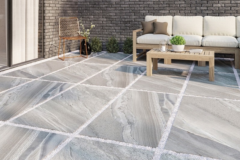 outside seating area with porcelain paving wooden table and chairs with white cushions