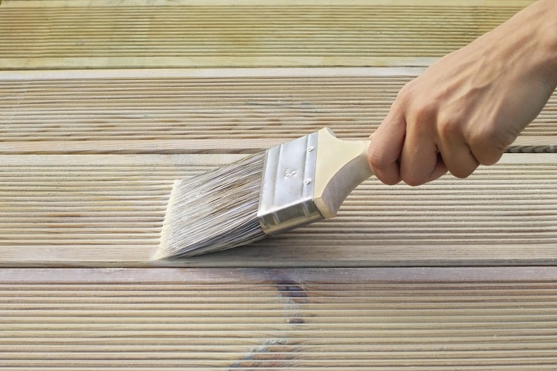 Man applyingwood treatment to keep decking lively